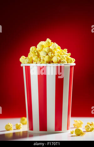 Red bowl full of popcorn on red background for film, TV, television watching. Concept of movie night Stock Photo