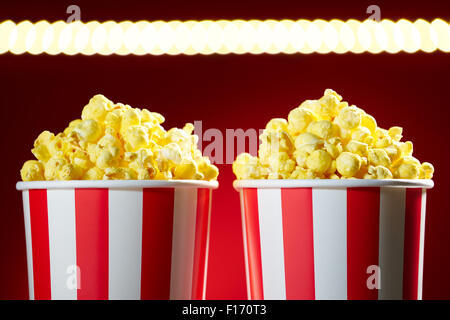 Two red bowls full of popcorns on red background for film, TV, television watching. Concept of couple having a movie night Stock Photo
