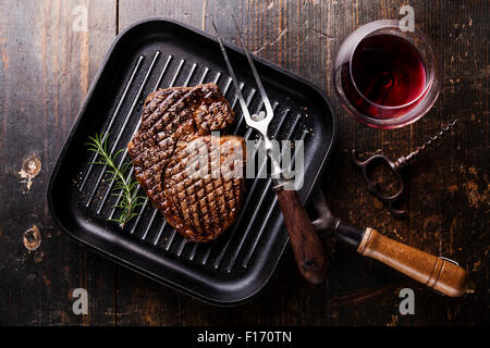 Grilled Black Angus Steak Ribeye on grill iron pan on wooden background with wine Stock Photo