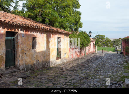 Red tile roofed stucco cottages on stone paved street in Colonia del Sacramento, Uruguay. The River Plate is visible beyond. Stock Photo