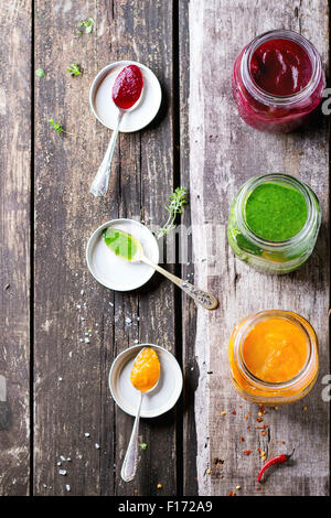 Assortment of vegetable smoothies from carrot, beetroot and spinach in glass jars. Over old wooden table with vintage spoons, he Stock Photo