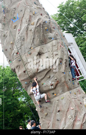Two young children climbing on a monolith rock wall Stock Photo