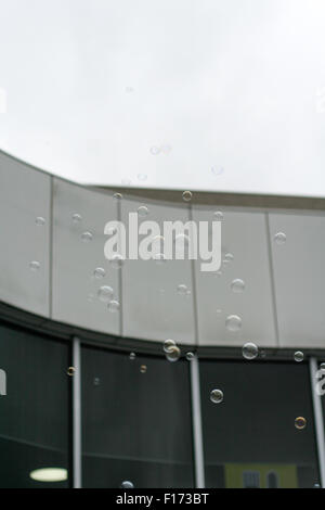 Bubbles floating in the air with modern building behind Stock Photo