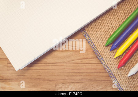 set of colored wax crayons and notebook on a natural burlap and wood ...