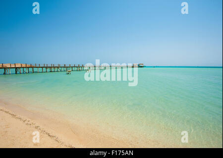 Long wooden jetty in the sea from a tropical island lagoon on beach Stock Photo