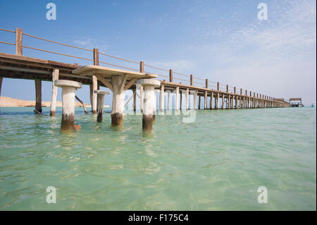 Long wooden jetty in the sea from a tropical island lagoon on beach Stock Photo