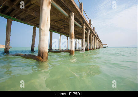 Long wooden jetty in the sea from a tropical island lagoon on beach Stock Photo