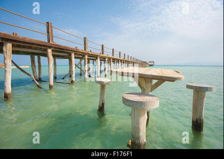 Long wooden jetty in the sea from a tropical island lagoon on beach Stock Photo