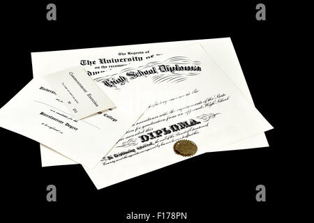 Education certification documents including high school diploma,commencement ticket, and university degree isolated on black Stock Photo