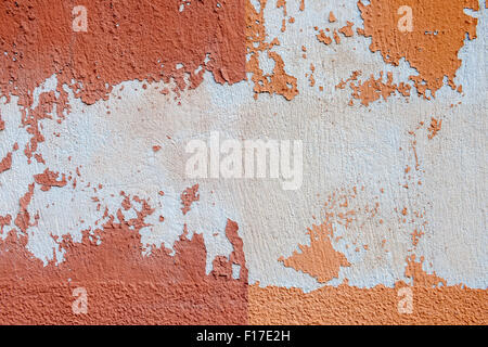 Abstract background of old vintage painted plastered wall with peeling paint and plaster texture in red orange colors Stock Photo