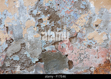 Old vintage painted plastered wall abstract background with many layers of worn paint in various colors and broken plaster textu Stock Photo