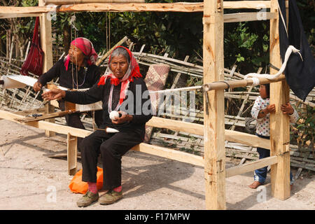 Old Dai women in a rural village in Xishuangbanna, Yunnan, China, weaving using a traditional wooden loom Stock Photo