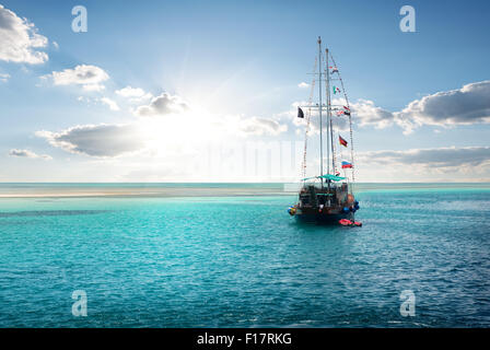 Yacht in the sea near island at sunrise Stock Photo