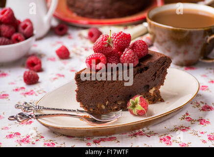 Homemade chocolate cake with raspberry on plate, cup of coffee and berries on side, selective focus Stock Photo