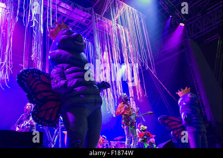 Portsmouth, UK. 29th August 2015. Victorious Festival - Saturday. Wayne Coyne of the Flaming Lips at the start of the headline set of the night on the Common Stage flanked by large inflatable creatures. Credit:  MeonStock/Alamy Live News Stock Photo
