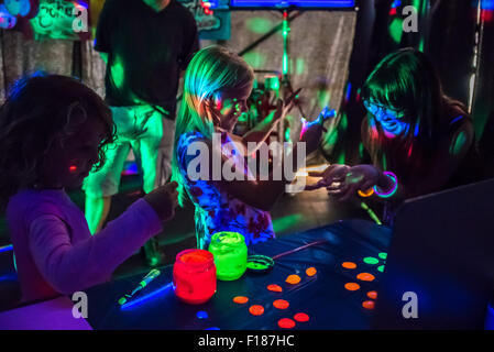 Brighton, UK. 29th Aug, 2015. 7 year old Zoe Cunliffe [centre] tries the luminescent face paint. Children and adults enjoy luminescent facepaint, colour changing ice cream and dayglo cocktails at the Brighton & Hove Festival Food and Drink Festival Boho Disco on Hove Lawns this weekend. Credit:  Julia Claxton/Alamy Live News Stock Photo