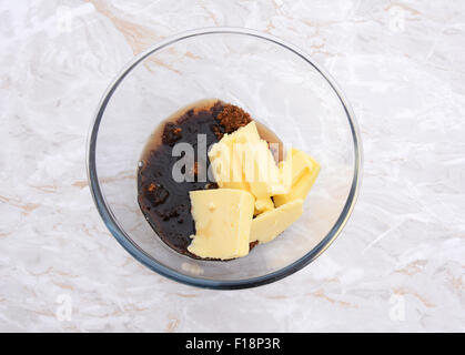 Maple syrup added to butter and dark muscovado sugar in a glass bowl - ingredients for pecan pie Stock Photo