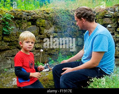 Man and four year-old boy toasting marshmallows on a fire, UK Stock Photo
