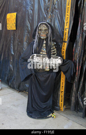 Witchy skeleton greeter with sign that says Enter if You Dare stands at the entrance of a haunted house Stock Photo