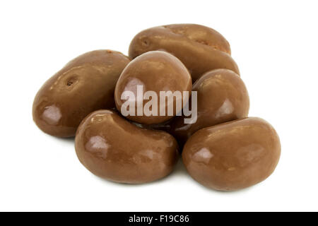 Close-up of a heap of peanuts covered in milk chocolate, isolated on white background. Stock Photo