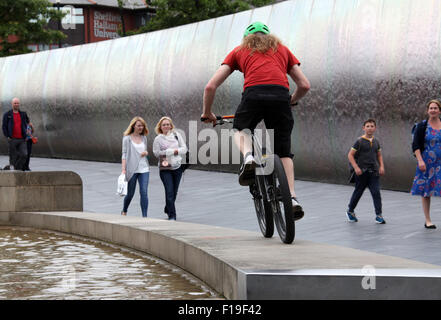 Stunt cyclist at the Cutting Edge steel sculpture and  water feature outside Sheffield Railway Station Stock Photo