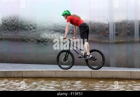 Stunt cyclist at the Cutting Edge steel sculpture and  water feature at Sheffield Railway Station Stock Photo