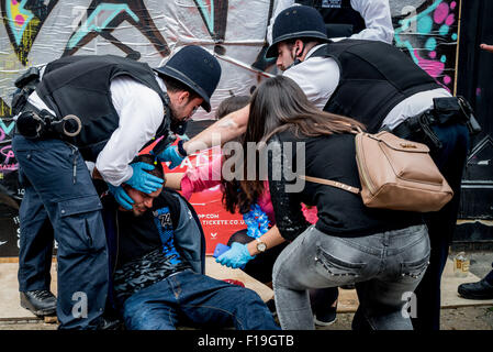 London, UK. 30th August, 2015. Metropolitan Police officers arrested unknown man during Notting Hill Carnival. He was bleeding and handcuffed from behind his back. After while he lost his consciousness. Members of the public was helping police to revive him.Metropolitan Police officers arrested unknown man during Notting Hill Carnival. He was bleeding and handcuffed from behind his back. After while he lost his consciousness. Members of the public was helping police to revive him. 30th Aug, 2015. Credit:  Velar Grant/ZUMA Wire/Alamy Live News Stock Photo