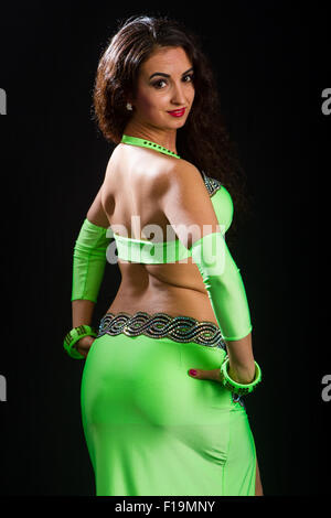 beautiful young brunette in a green suit oriental dance on black background Stock Photo