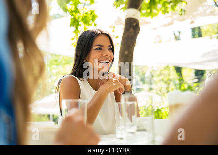 Portrait of a laughing woman sitting at the table in outdoor restaurant Stock Photo