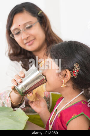 Indian family dining at home. Photo of child drinking water on dining table. Traditional home cook meal. Stock Photo