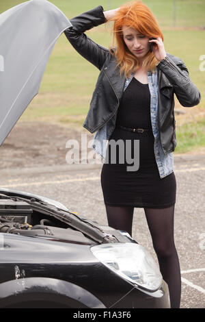 A car breakdown, a woman on her phone next to her car. Stock Photo