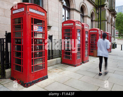 People passing K6 Old type GPO, or BT red Telephone Boxes advertised as being  'To Let' with various uses being suggested by the agent. Preston, UK Stock Photo
