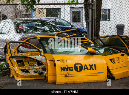 Scrapped yellow  New York Taxi Cab doors piled up against a fence at a vehicle scrap Yard in Long Island City, Queens, New York ,USA Stock Photo