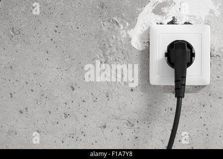 Energy, Electric Plug on a concrete wall Stock Photo