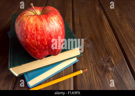 Old books and red apple on wooden background with copy space Stock Photo