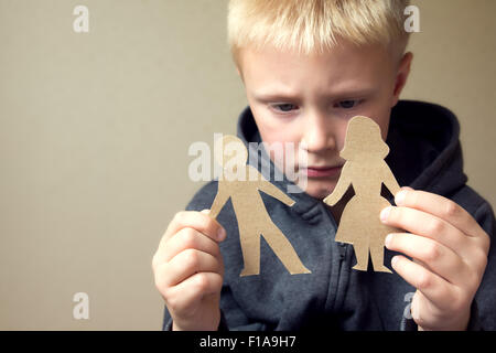 Confused child with cutting paper parents, family problems, divorce, custody battle, suffer concept Stock Photo