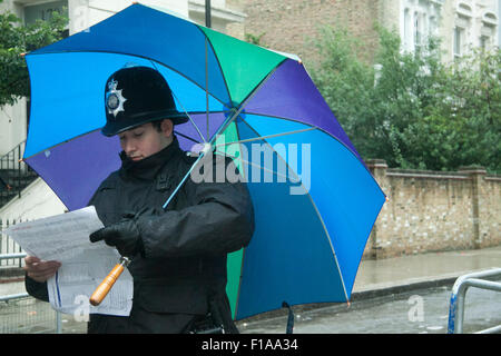 Notting Hill London,UK. 31st August 2015.  A policeman sheltering from the rain at  the Notting Hill Carnival,Europe's biggest street festival on August bank holiday Credit:  amer ghazzal/Alamy Live News Stock Photo