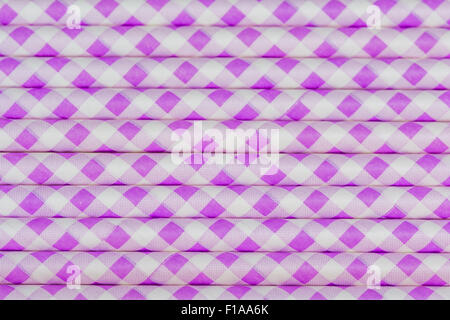 Party straws stacked to provide an purple and white patterned background Stock Photo