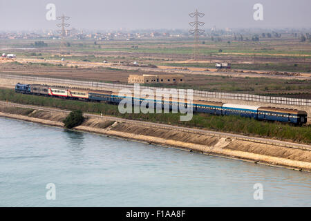 Early morning commuter train passing alongside Suez Canal Egypt. Stock Photo