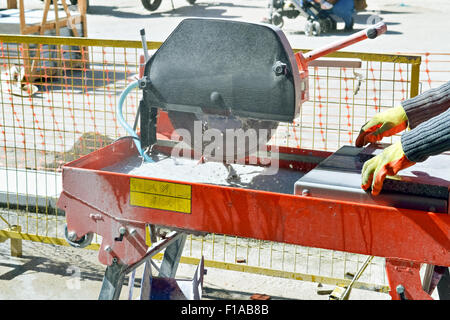 Manual worker that cuts concrete slabs for paving the street Stock Photo