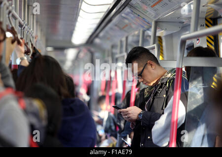 Hong Kong, China, man looking at a subway compartment on his smartphone Stock Photo