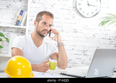 a young engineer talking on the phone and drinking coffee Stock Photo