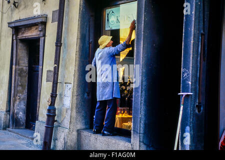 A mature man window cleaning a shop window. Krakow. Poland. Europe Stock Photo