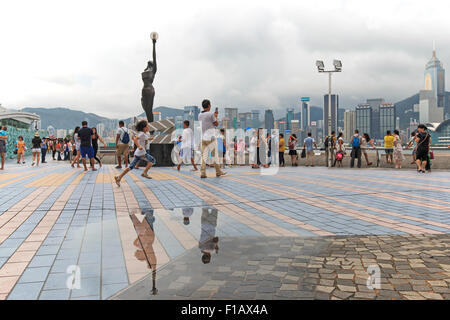 Hong Kong, China - August 14, 2015: Tourists walking near the bronze statue of Hong Kong Film Awards and skyline in Avenue of St Stock Photo