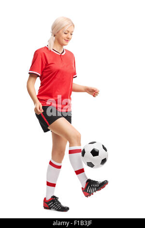 Full length portrait of a female soccer player juggling a ball and smiling isolated on white background Stock Photo