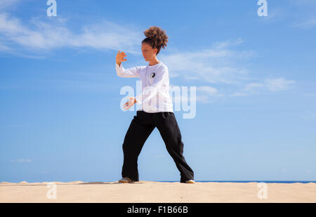 Tai chi in the dunes - young woman in black and white making tai chi moves Stock Photo