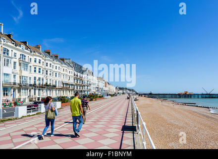 The seafront promenade and beach with the burnt out pier in the distance, Hastings, East Sussex England, UK Stock Photo