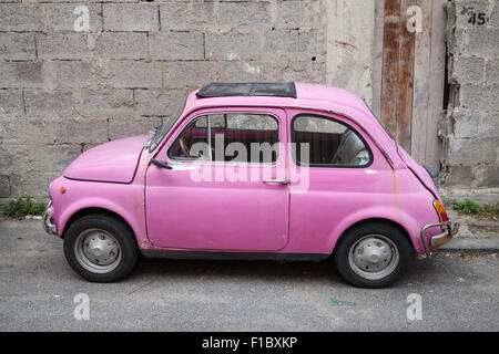 Lacco Ameno, Italy - August 15, 2015: Old pink Fiat Nuova 500 city car produced by the Italian manufacturer Fiat between 1957 an Stock Photo