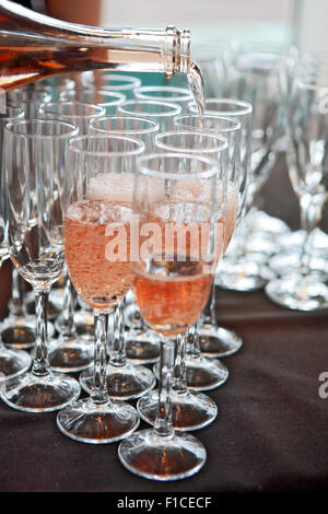 Pink champagne being poured into champagne flutes Stock Photo