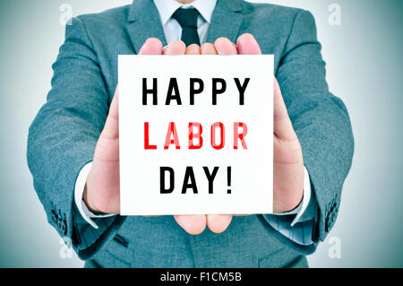 closeup of a young man in suit showing a signboard with the text happy labor day written in it Stock Photo